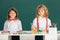 School smiling children girl and boy painting with paints color and brush in classroom on school blackboard background