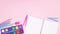 School supplies and open notebook appear on bottom of pastel pink background - Stop motion