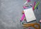 School supplies for school: notepad, pencils, pink ruler, compasses scattered on a gray table. Top view.