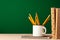 School supplies on wooden desk against green chalkboard