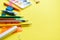 School supplies on a yellow background with place for text. Scissors, paints, pencils, children`s stationery