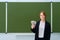 School teacher holds money in us dollars and smiles on blackboard background, copy, space