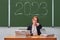 School teacher points a finger forward, blackboard with the text 2023 y