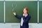 School teacher stands at the blackboard with a chalk drawn question mark. The female teacher stands with a thoughtful face