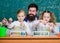 School time. Schoolgirls holding test tubes guided by teacher. School children performing experiment in science