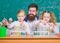 School time. Schoolgirls holding test tubes guided by teacher. School children performing experiment in science