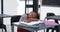 In a school, a young biracial girl rests her head on a desk