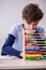 Schoolboy with abacus studying math at home