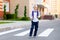 A schoolboy boy with blond glasses and a backpack is standing at the school. Day of knowledge