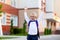 A schoolboy boy with blond glasses and a backpack is standing at the school. Day of knowledge