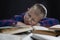 Schoolboy boy with glasses sleeps on books. Black background. Distance learning during the coronavirus pandemic