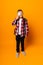 Schoolboy boy looking through a magnifying glass, enlarging his eye on a yellow background