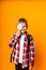 Schoolboy boy looking through a magnifying glass, enlarging his eye on a yellow background