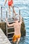 Schoolboy climbs up pier on ladder against clear seascape