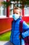 Schoolboy is closed eyes wearing protective mask Standing near school. students are ready for second pandemic wave