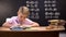 Schoolboy doing sums on math lesson, sitting against blackboard, knowledge