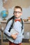 Schoolboy dressed in glasses and a backpack standing in the classroom