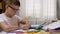 Schoolboy in Glasses Writes with Pen in Notebook Does Homework Use Smartphone