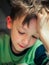 schoolboy with great reluctance reads a book and holds his head in his hand