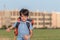 The schoolboy happily runs with a backpack on the field against the background of the city landscape