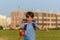 The schoolboy happily runs with a backpack on the field against the background of the city landscape