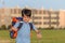 The schoolboy happily runs with a backpack on the field against the background of the city landscape selective focus