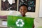 Schoolboy holding a green crate with a white recycling logo on it