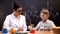 Schoolboy holding test tube with orange liquid observing reaction with teacher