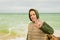 Schoolboy in jacket with hood poses for camera against sea and coastline on horizon closeup