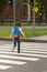 Schoolboy with a knapsack behind his back runs across the road a