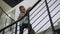 Schoolboy leaning stairs railing looking corridor. Boy standing stairway alone.