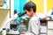 The schoolboy looks through a microscope in a laboratory with curiosity.  Children came on an excursion to the clinic