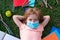 A schoolboy in a mask lies on the grass and dreams. Schools are closed for quarantine. Coronavirus pandemic and children