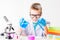 A schoolboy with a microscope and book examines chemicals in test tubes, conducts experiments - a portrait on a white background.