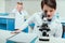 Schoolboy with microscope and copybook in science laboratory