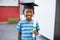 Schoolboy in mortar board holding certificate in classroom