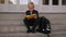 A schoolboy opens a lunch box with food sitting on the steps of the school.