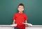 Schoolboy with paper plane play near a blackboard, empty space, education concept