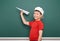 Schoolboy with paper plane play near a blackboard, empty space, education concept
