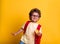 A schoolboy preparing for lunch isolated on yellow background. Kid in glasses with backpack ready to kindergarten or