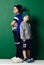 Schoolboy and preschooler in modern sportswear knitted hats, pants, shorts, hoody and t-shirt cool posing back to back