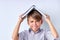 schoolboy put book on his head, looking at camera irritated. kid boy having fun with homework