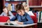 Schoolboy Reading Book At Table In Library