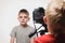 Schoolboy is ready to give the interview, blond boy with the video camera. Young video blogger. White background