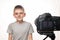 Schoolboy is ready to give the interview on a camcorder. Young video blogger. White background