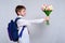 Schoolboy with a school bag gives a bouquet of tulips. White background