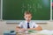 Schoolboy sits at a desk at school classroom