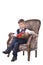 Schoolboy sitting in an antique-designed chair and reading book