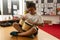 Schoolboy sitting on desk and playing bongo in a classroom