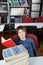 Schoolboy Sitting With Stacked Books At Table